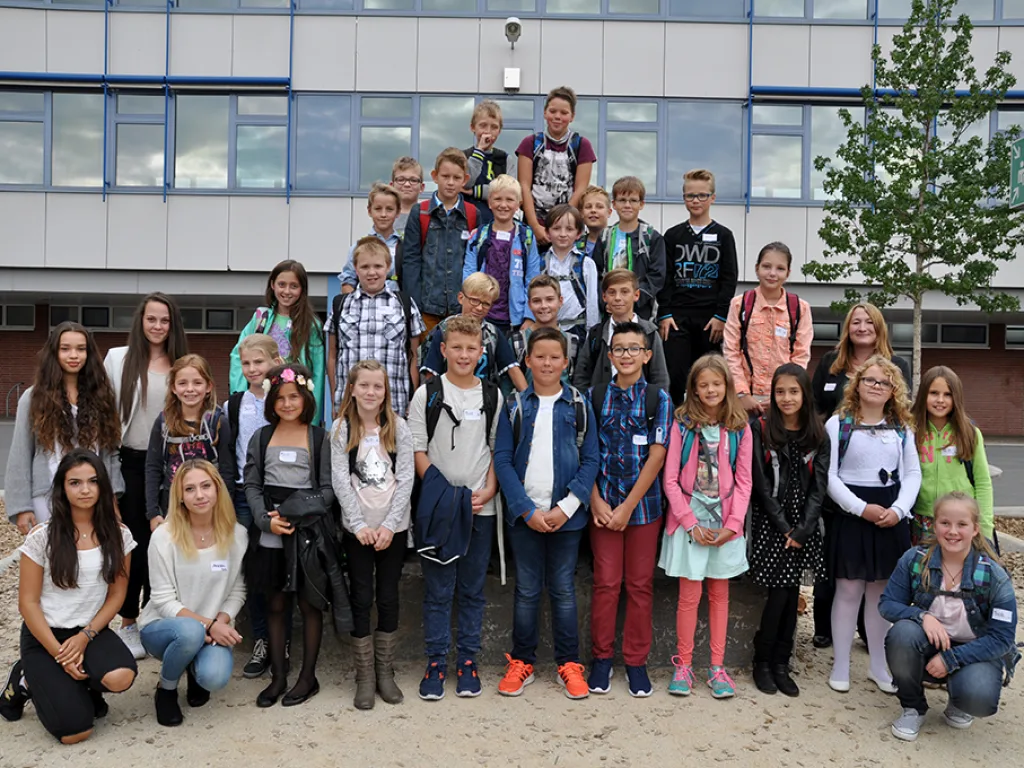 Klassenfoto einer neuen fünften Klasse vor der blauen Fassade.